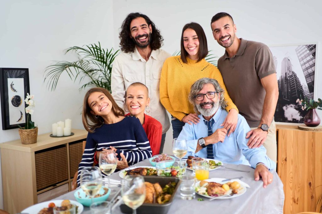 A group of six people smiling around a table with food and drinks.