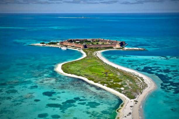 Aerial view of a small island with Fort Jefferson, surrounded by clear blue waters and narrow sandy paths in Dry Tortugas National Park.
