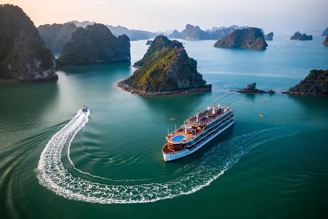 Two boats navigate the turquoise waters surrounded by rocky islets. One boat creates a wake as it moves away, while a larger cruise ship remains stationary nearby.