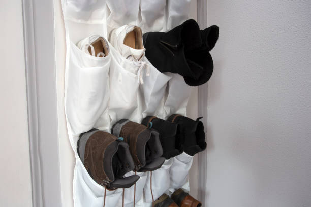 Boots stored in a white hanging organizer on a wall.