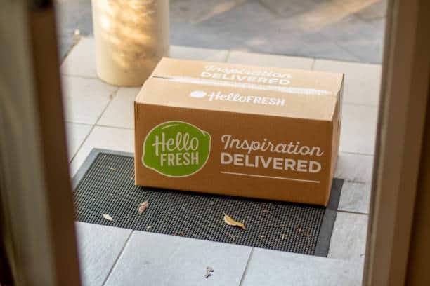A HelloFresh delivery box sits on a doormat outside a doorway.