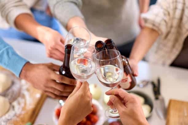 A group of people clink glasses and bottles in a celebratory toast.