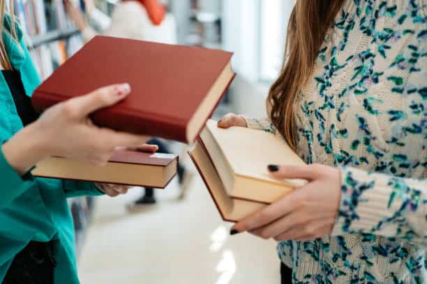 Two people exchange books in a library.