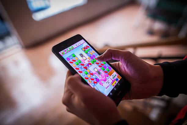 Person playing a colorful puzzle game on a smartphone indoors.