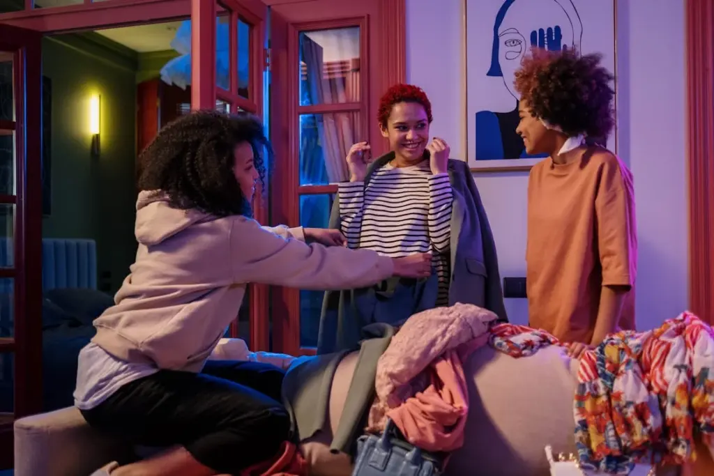 Three people sorting through clothes on a sofa, with one holding up a striped shirt.