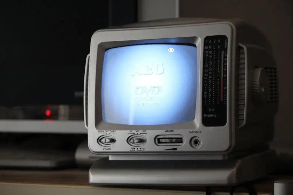 Small vintage TV displaying a DVD screen with tuning knobs, volume controls, and an earphone jack on the front panel.